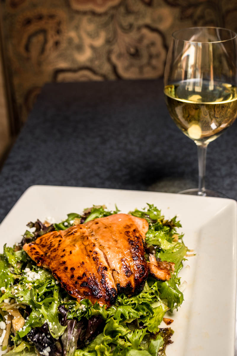 Plated Harvest Salmon Salad - Mixed greens, maple-Dijon vinaigrette, toasted walnuts, pears, blueberries, goat cheese, caramelized salmon with glass of white wine.