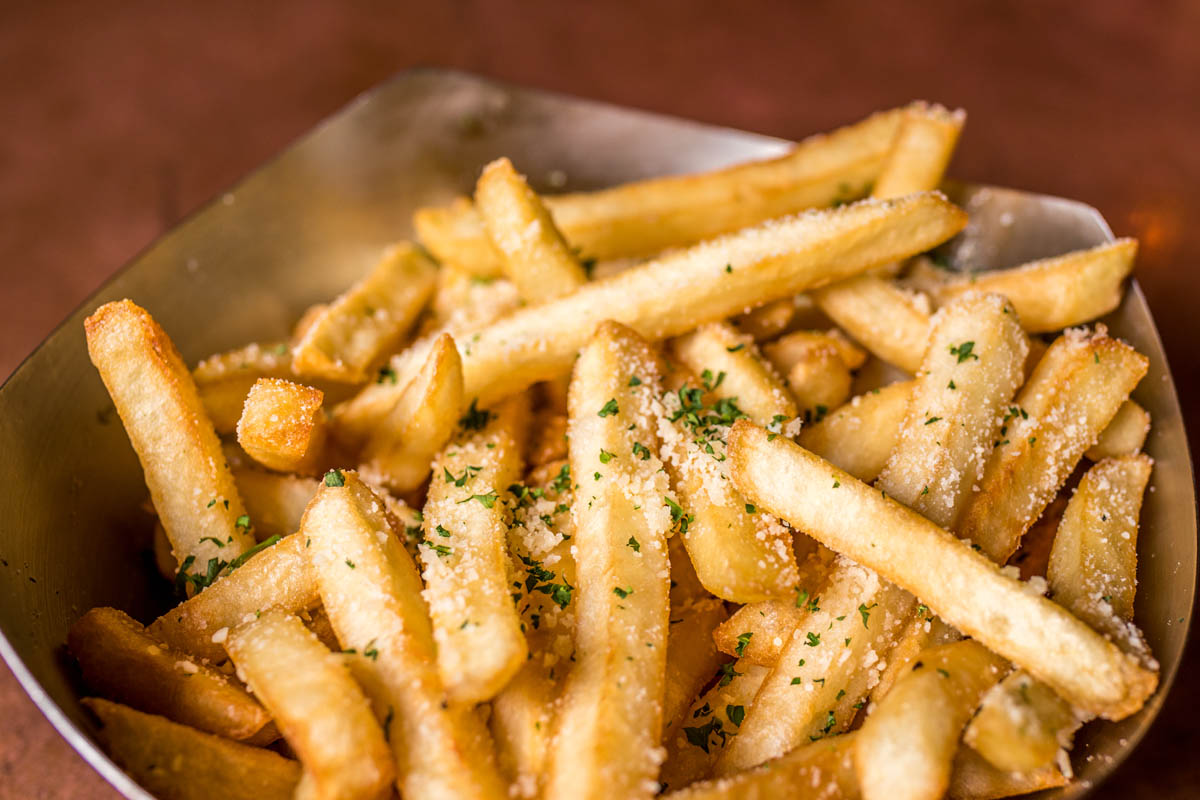 Close-up of seasoned French fries in metal bowl.