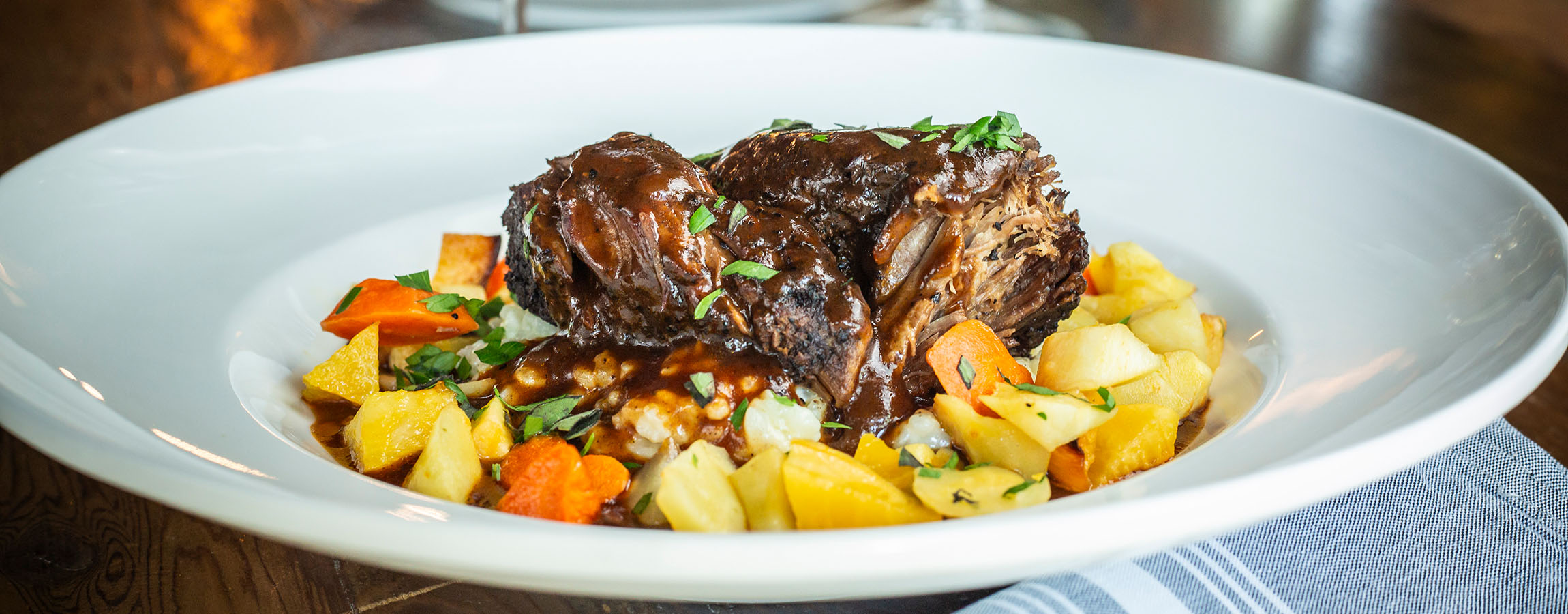 Braised Short Ribs plated on root vegetables, served at Napa Kitchen & Bar.