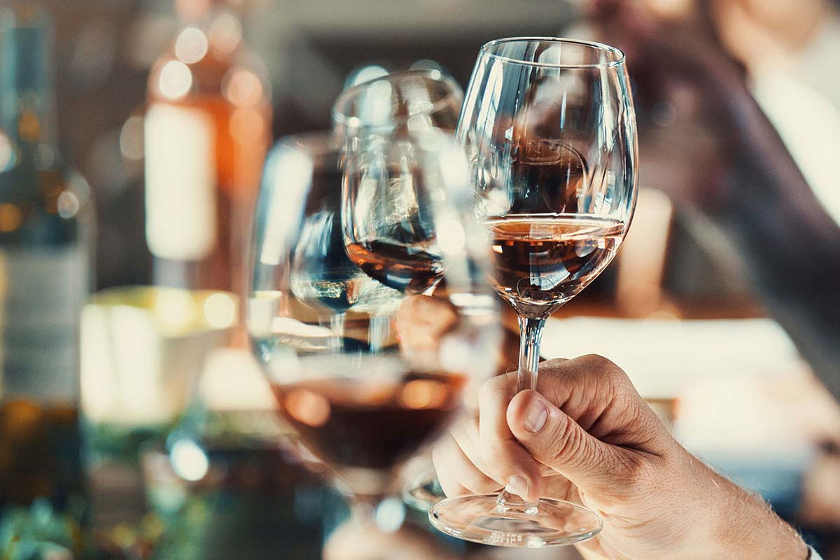 Hand holding up a glass of red wine at a wine tasting.